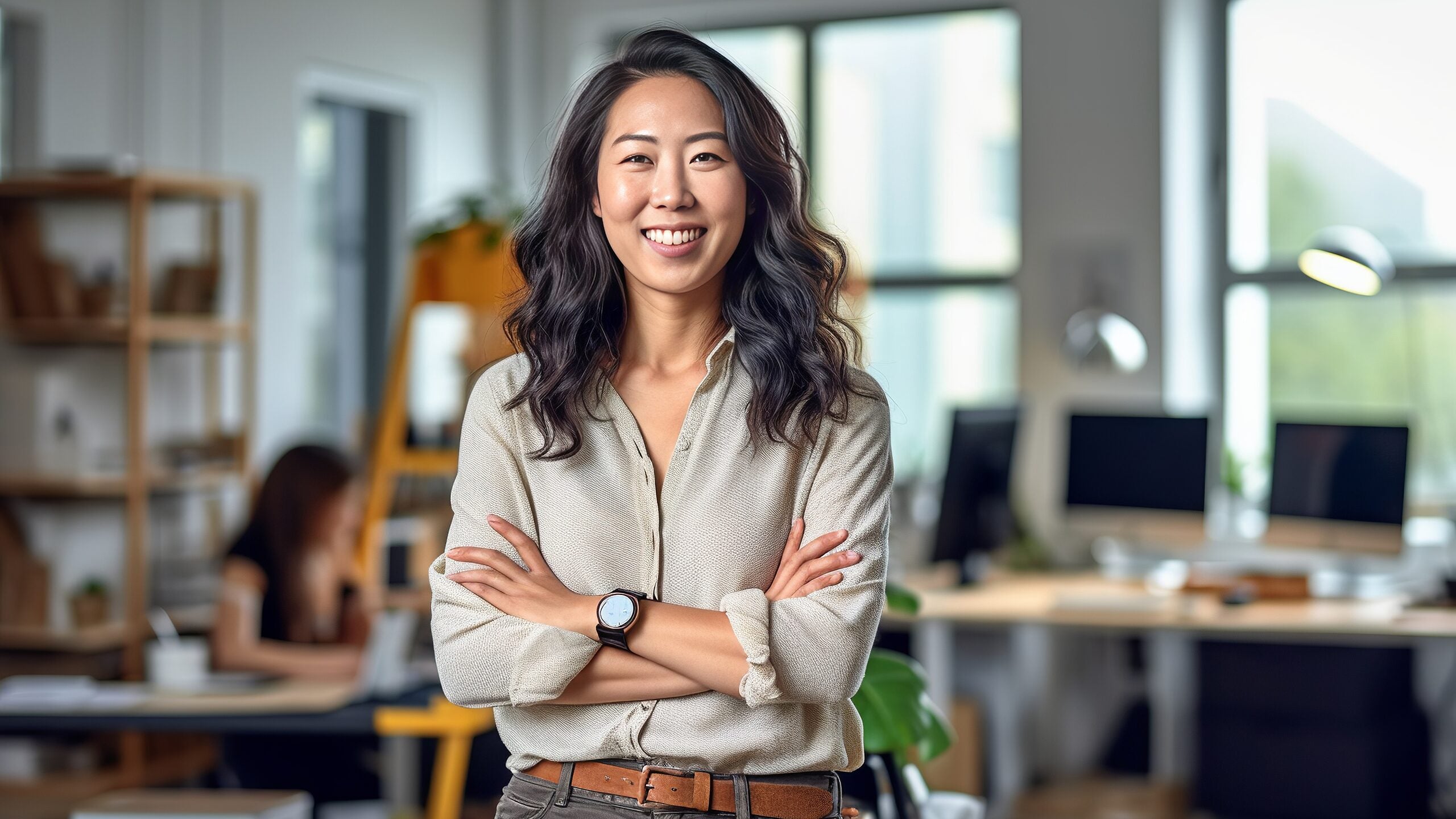 Woman with crossed arms, standing in a workspace.
