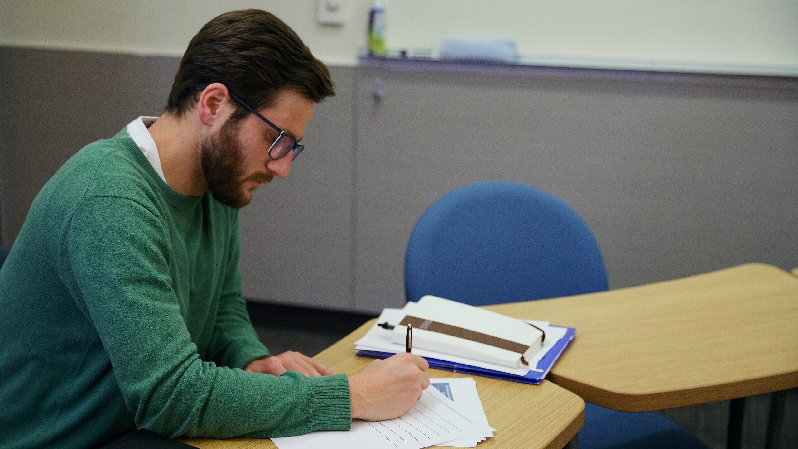 Student taking notes in classroom.