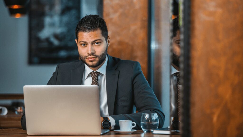 Man in suit working on laptop in restaurant.